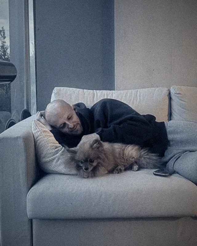 Flavien asleep on a sofa with POPI curled up next to him